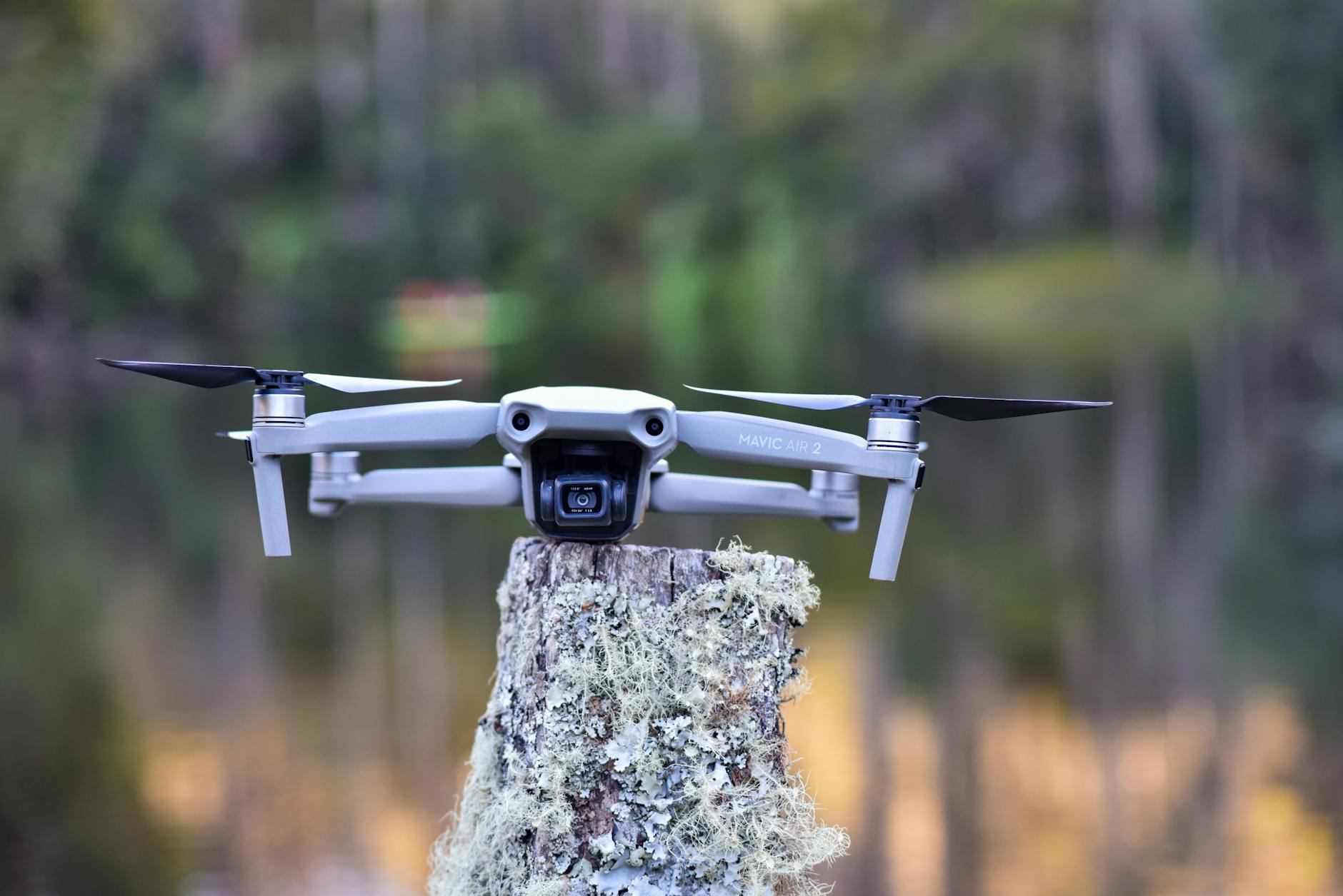 Close-up of a Mavic Air 2 drone resting on a mossy tree stump in a serene outdoor setting.