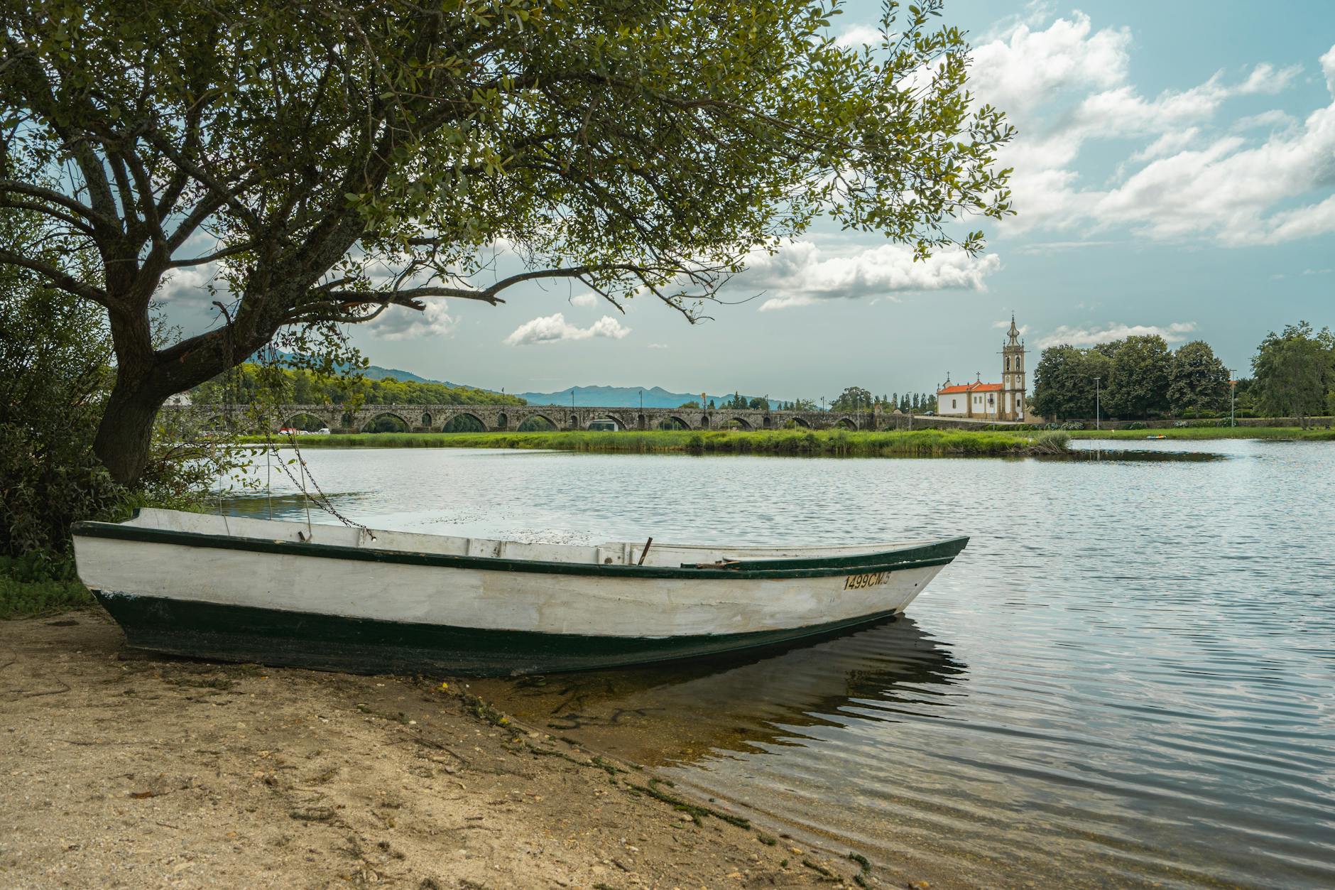 Tranquil scene of a boat on the Lima River in Ponte de Lima, Portugal, with a picturesque backdrop.