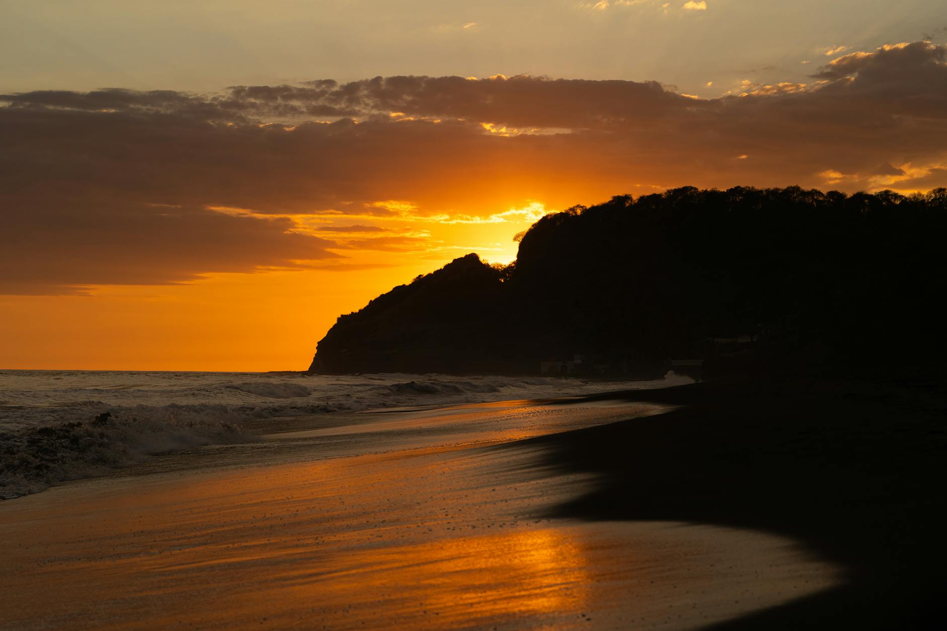 A breathtaking sunset over a tranquil beach in El Salvador with vivid orange hues.