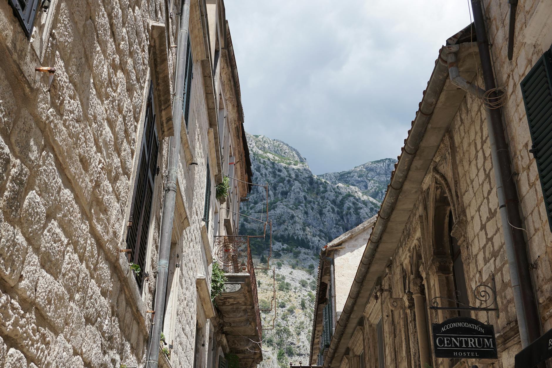 Stone buildings and mountain backdrop in Kotor, Montenegro create a picturesque view.