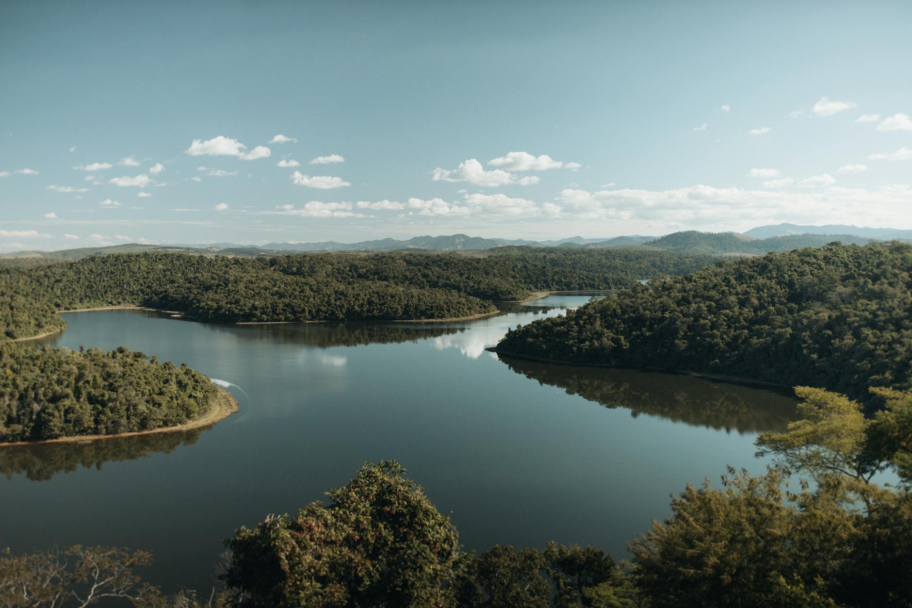 A picturesque view of a serene river winding through lush forests in Minas Gerais, Brazil.