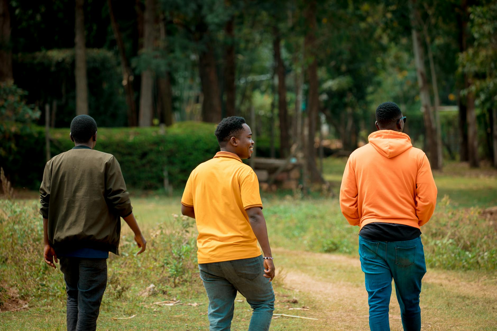 Three men walking on a garden path in Homa Bay, Kenya. Casual and serene outdoor scene.