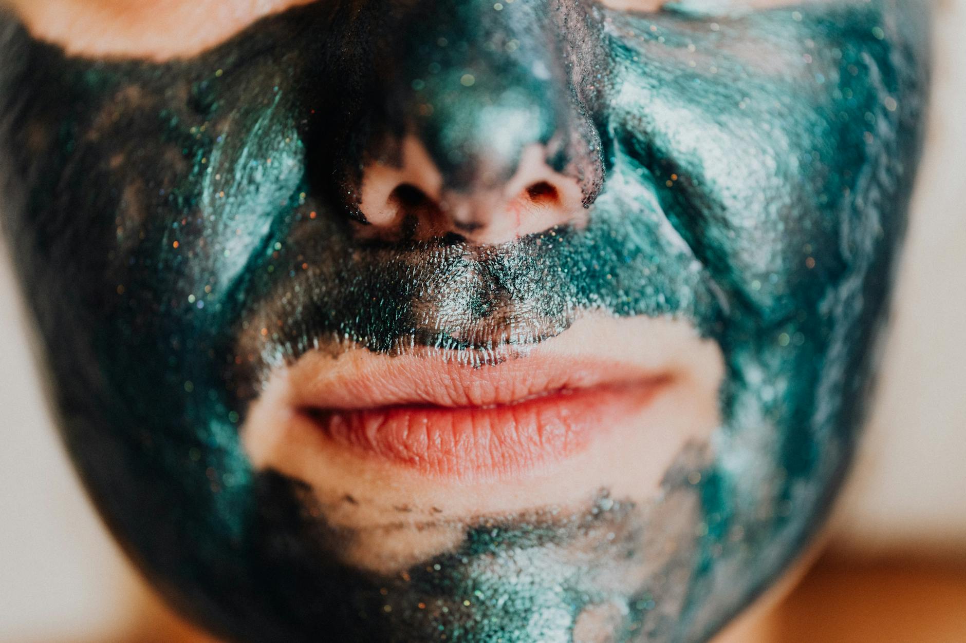 Intimate close-up of a person wearing a shimmering green facial mask promoting skincare.