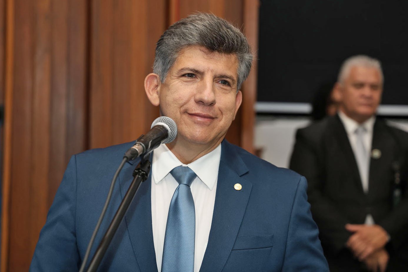 Representação de discussão entre dois parlamentares em plenário, com símbolos da justiça ao fundo, ilustrando a investigação.