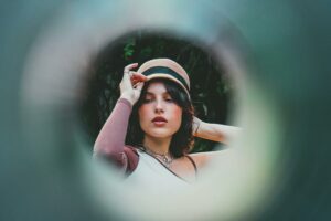 Fashionable woman wearing a hat poses creatively. Shot through a circular frame in São Paulo, Brazil.