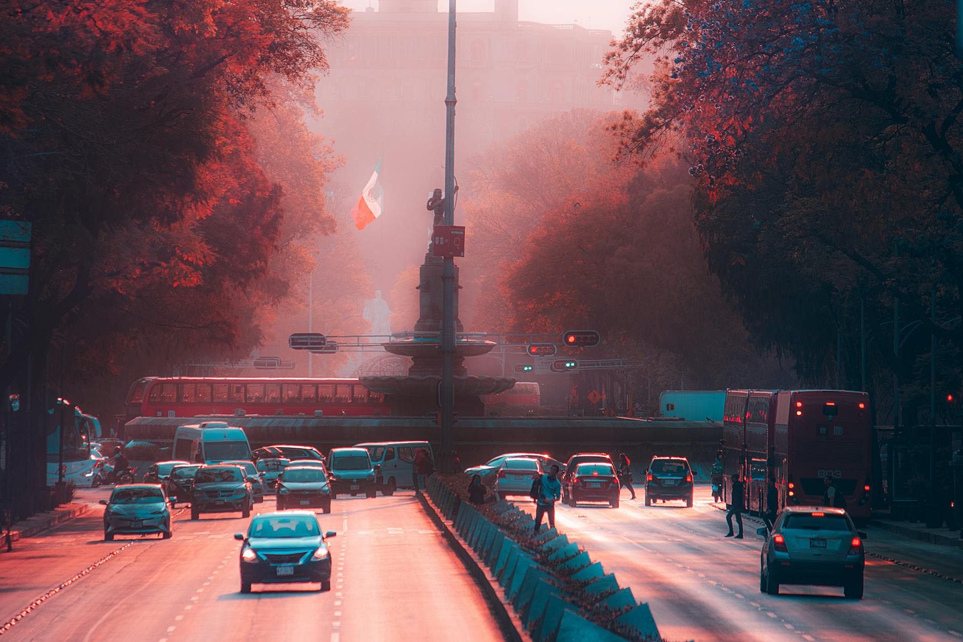 Evening traffic on Paseo de la Reforma in Mexico City with vibrant lighting and the Mexican flag in view.
