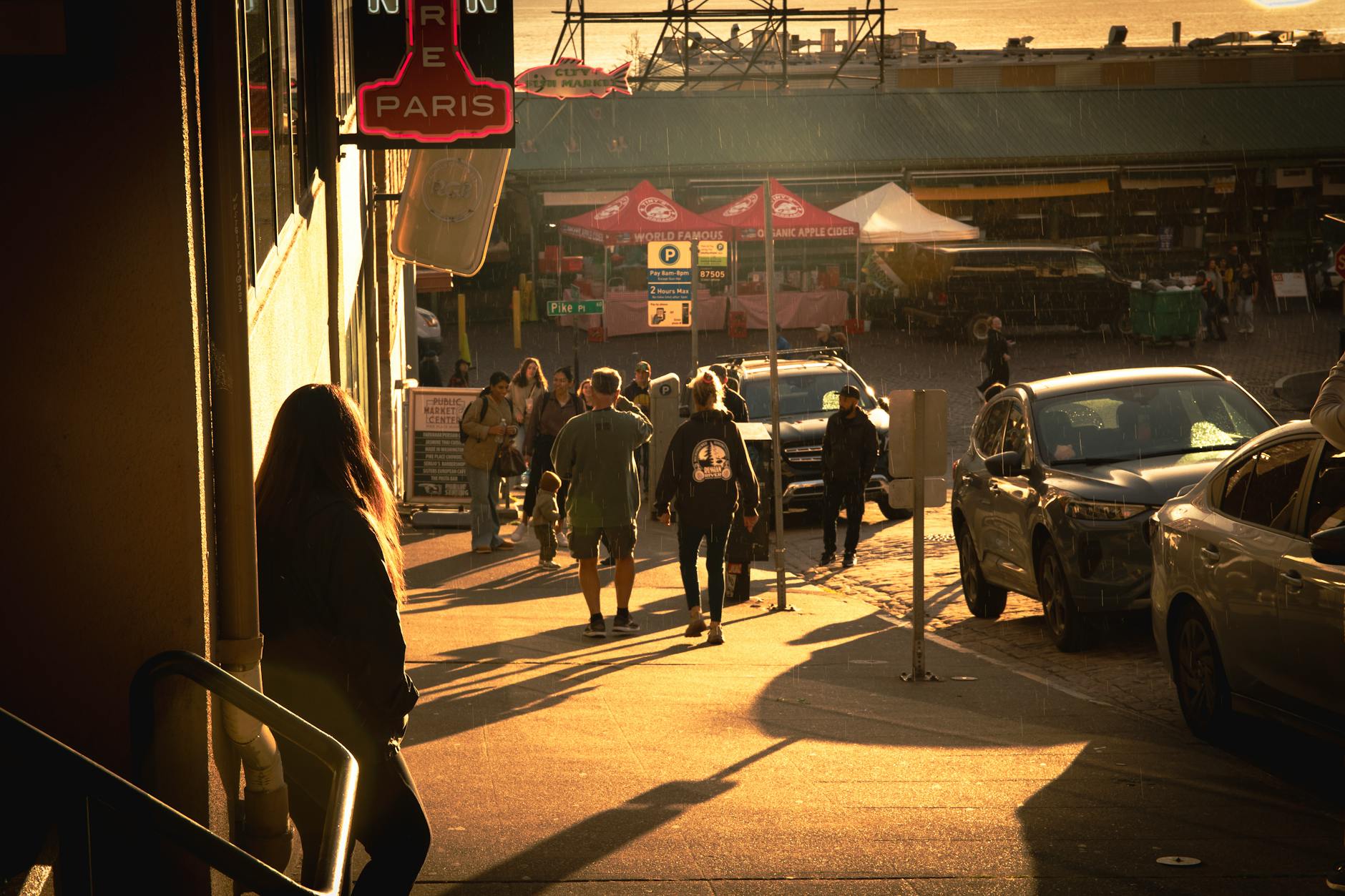 Street scene in Seattle with people walking during a rainy sunset, creating a warm urban ambiance.