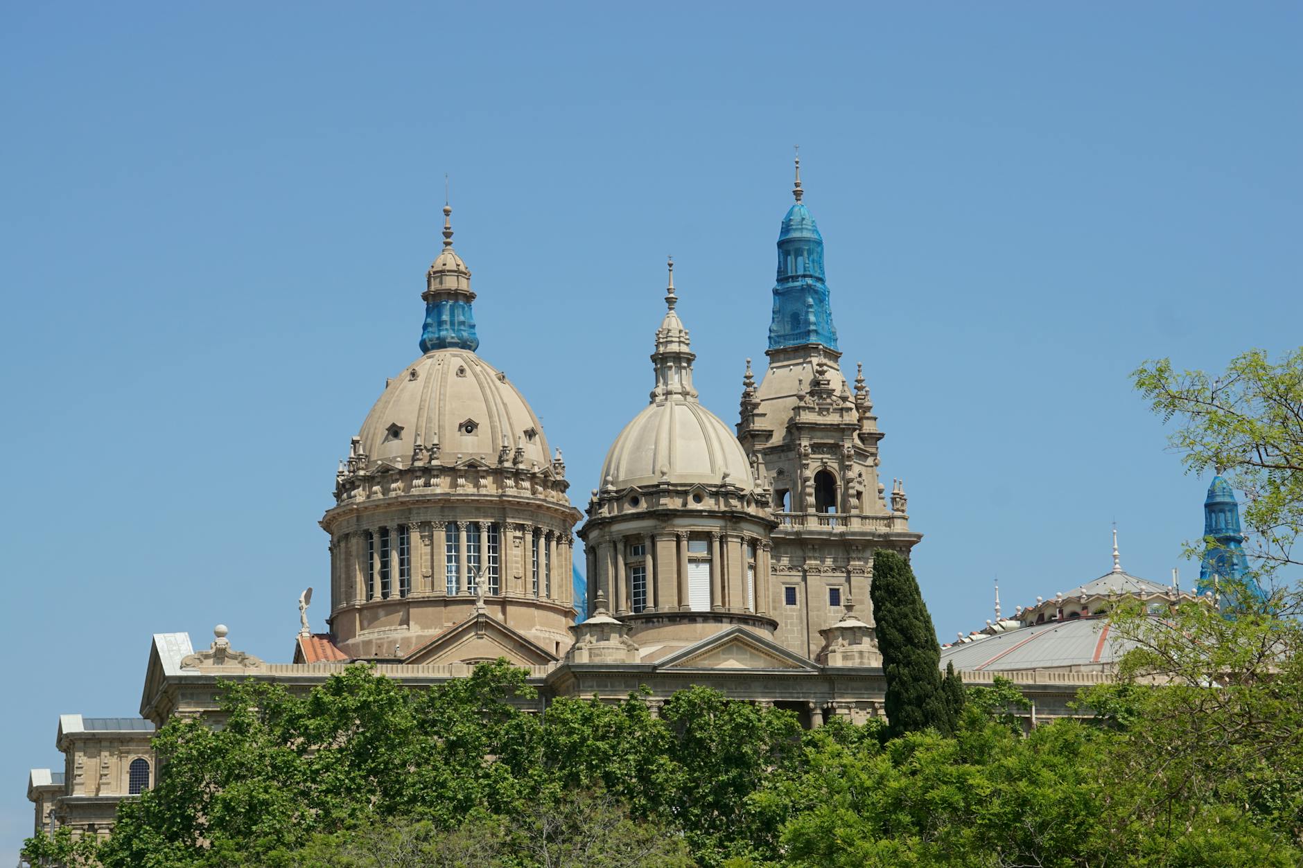 The National Palace in Barcelona, showcasing its grand architectural domes against a clear sky.