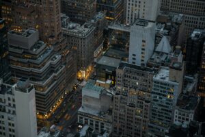 A dramatic aerial view of illuminated skyscrapers in Manhattan, New York City, showcasing urban architecture and city life at night.
