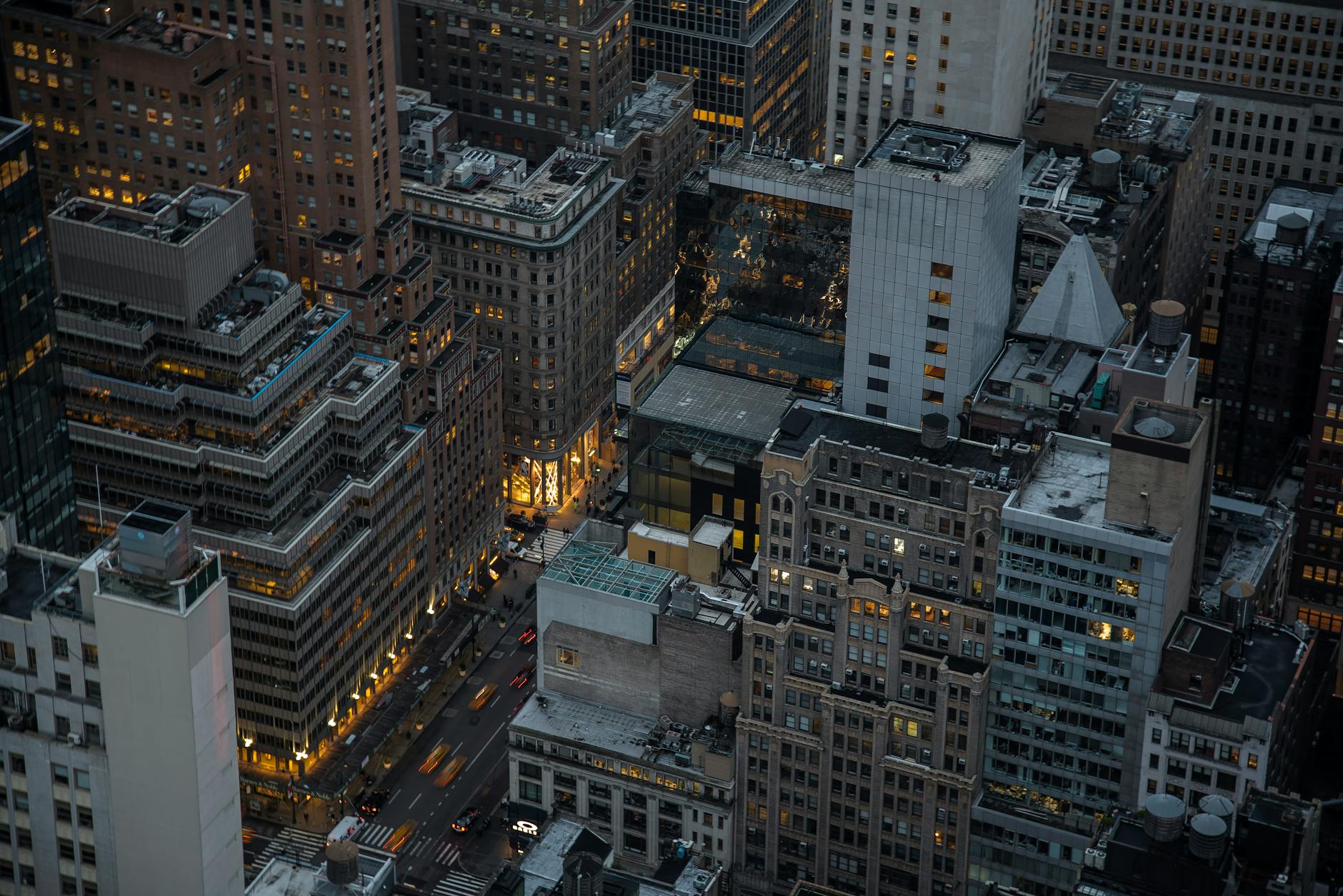 A dramatic aerial view of illuminated skyscrapers in Manhattan, New York City, showcasing urban architecture and city life at night.