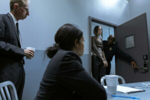 Officers escorting a handcuffed suspect into an interrogation room during a criminal investigation.
