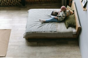 Woman reading a book in a cozy minimalist bedroom, viewed from above for a serene ambiance.