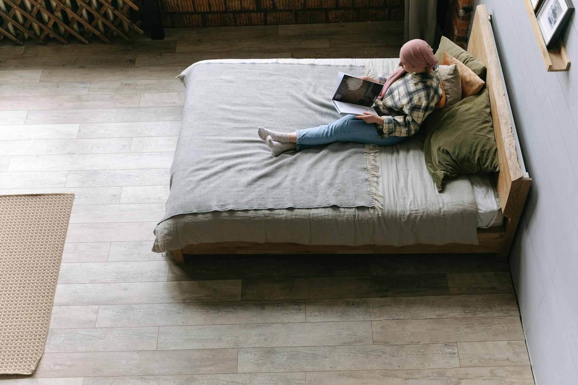 Woman reading a book in a cozy minimalist bedroom, viewed from above for a serene ambiance.