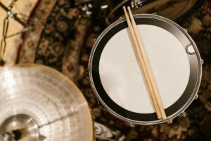 Overhead shot of drumsticks resting on a snare drum in a music studio.