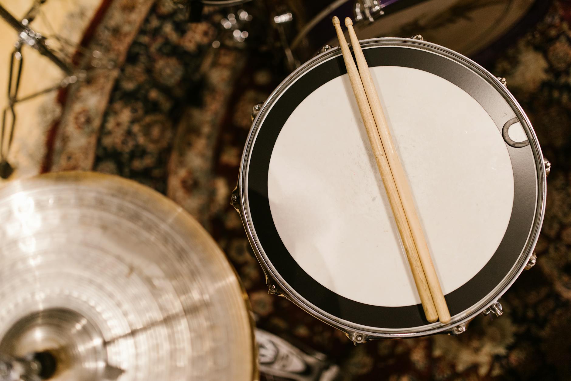 Overhead shot of drumsticks resting on a snare drum in a music studio.