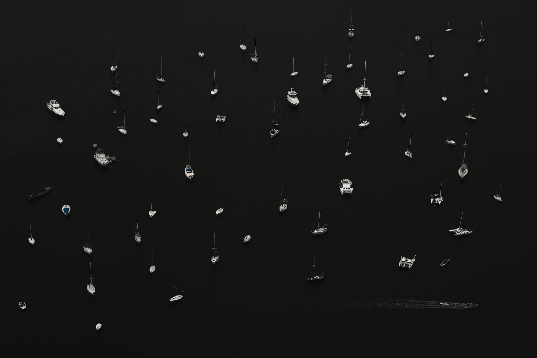 Aerial shot of numerous boats on calm dark waters in Rio de Janeiro, creating a striking pattern.